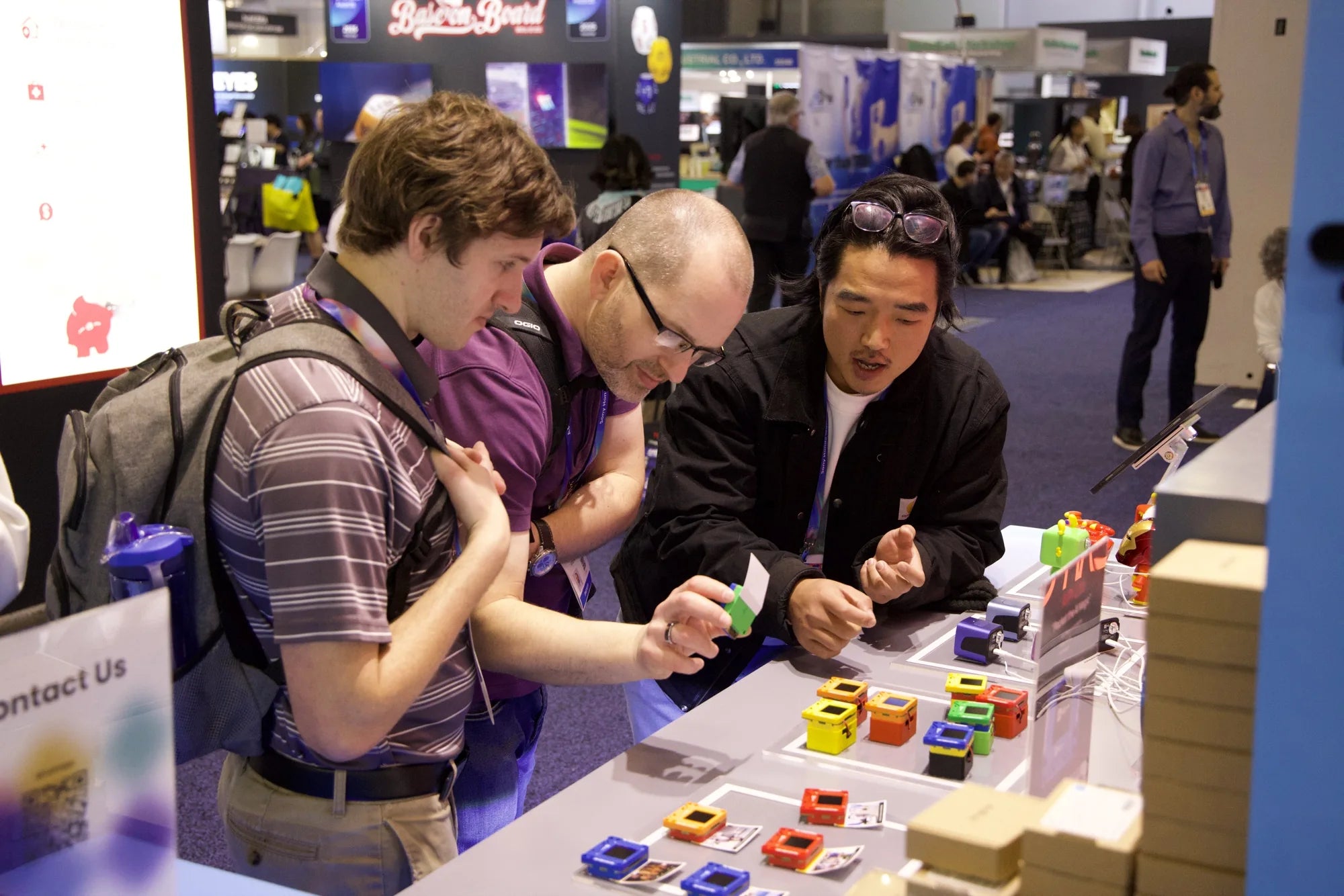 CES visitors inspecting a colorful AIPI Lite device while talking with a team member
