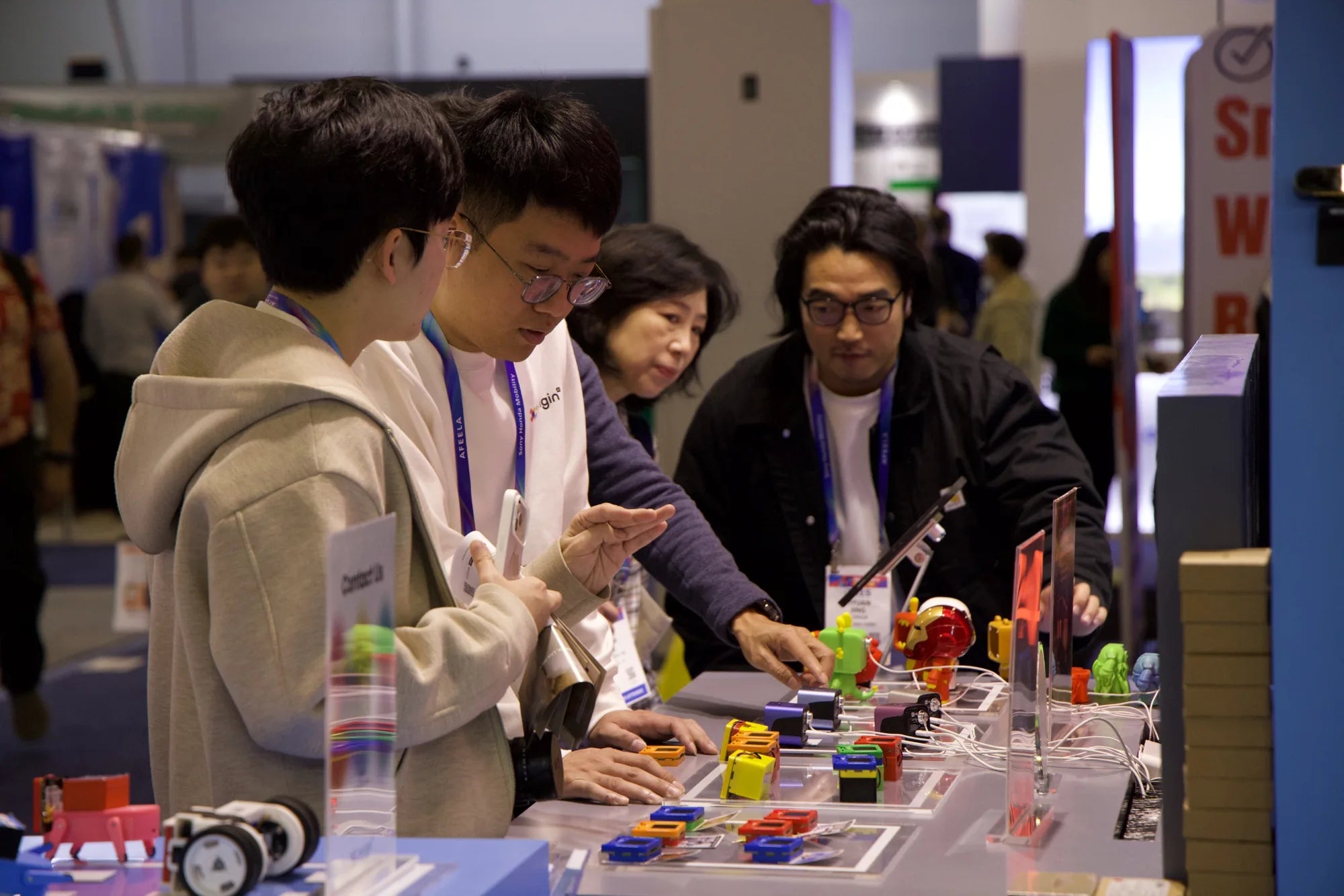 X-Origin team member and CES visitors examining AIPI devices at the display table